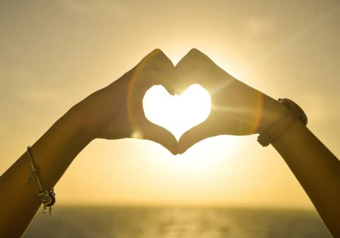 handen die een hartje vormen tegen een achtergrond van zonsondergang