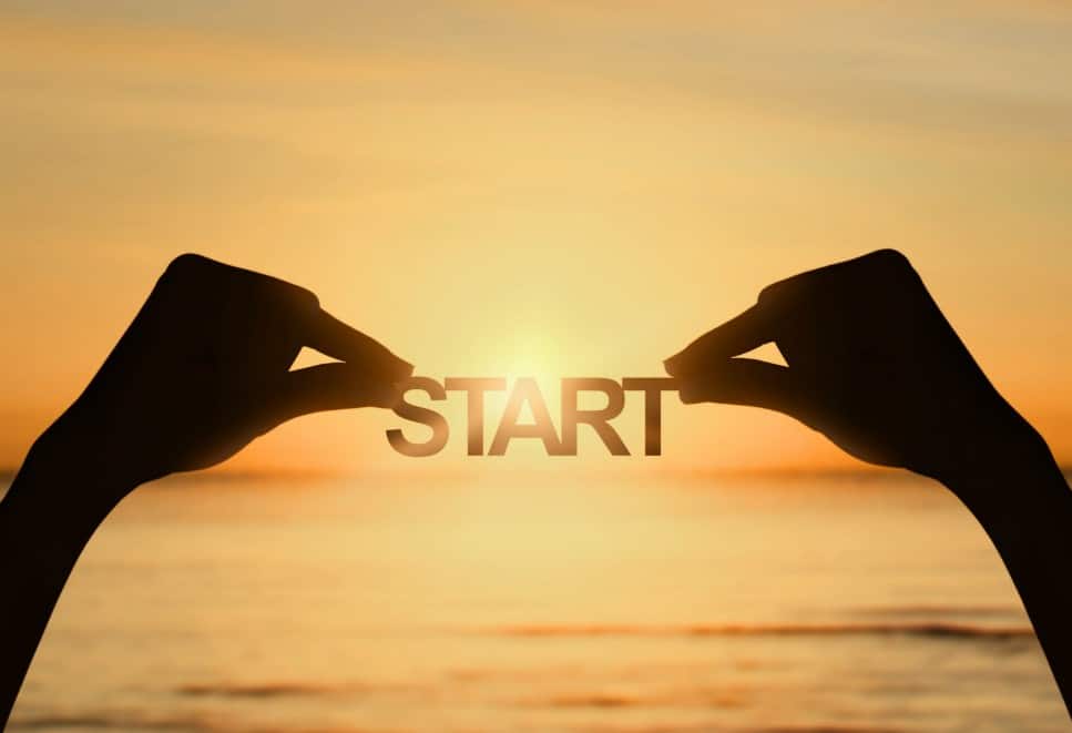 twee handen die het woord START vasthouden tegen een achtergrond van zonsondergang
